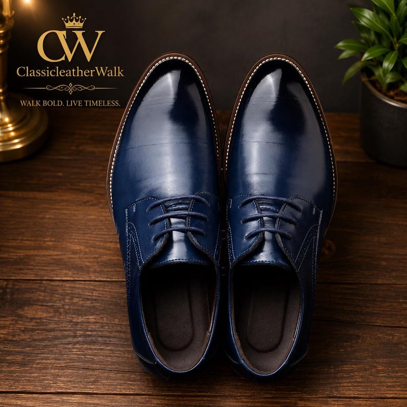 May include: A pair of polished navy blue leather oxford shoes with lace-up closures, rounded toes, and visible white stitching along the welt. The logo CW ClassicleatherWalk and the text WALK BOLD. LIVE TIMELESS. are printed in gold.