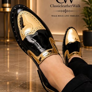 Op de afbeelding: Een zwarte en gouden lakleren loafer met brogue-details op de neus en zijpanelen. De schoen heeft een glanzende metallic gouden afwerking op de neus en kraag, gecombineerd met zwart lakleer. Tekst: CW ClassicleatherWalk.