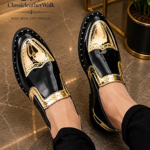 Op de afbeelding: Een paar zwart-gouden instapschoenen met een hoogglanzende lakafwerking, metallic gouden neuzen en gouden zijpanelen met decoratieve perforaties. De schoenen zijn voorzien van de tekst CW ClassicleatherWalk WALK BOLD. LIVE TIMELESS.