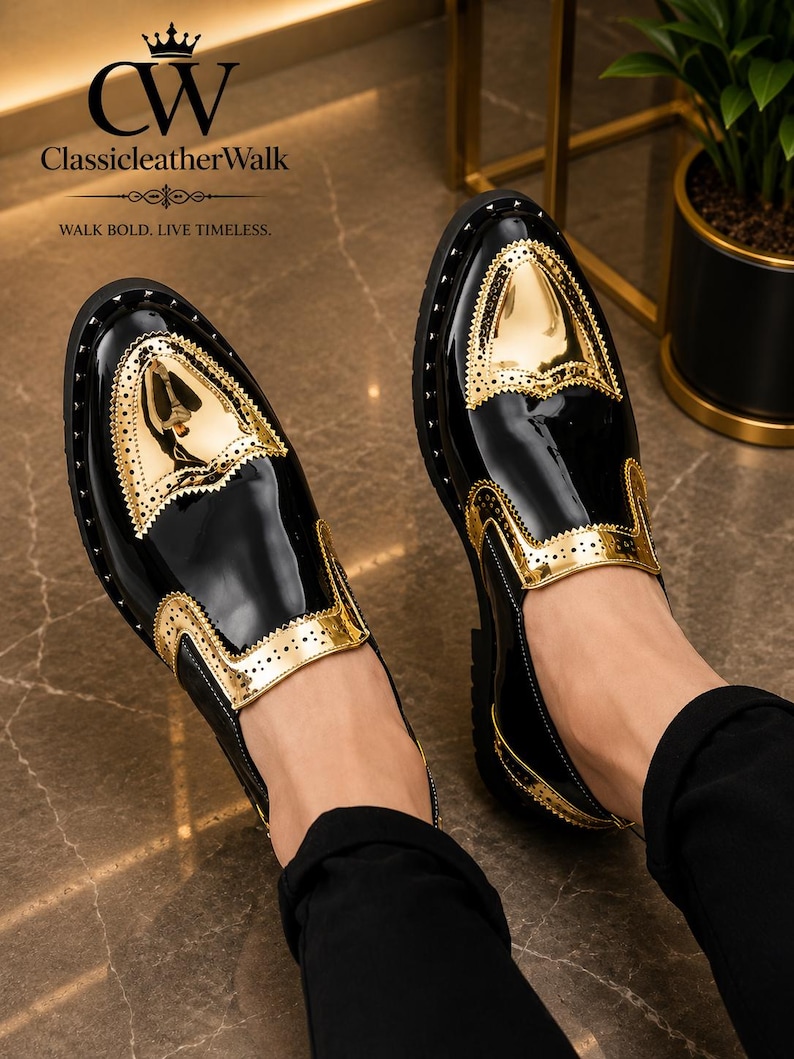 Op de afbeelding: Een paar zwart-gouden instapschoenen met een hoogglanzende lakafwerking, metallic gouden neuzen en gouden zijpanelen met decoratieve perforaties. De schoenen zijn voorzien van de tekst CW ClassicleatherWalk WALK BOLD. LIVE TIMELESS.