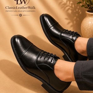 May include: A pair of black leather cap-toe oxford shoes with black laces and a low heel. The text GW ClassicLeatherWalk STEP INTO CLASS. WALK WITH CONFIDENCE. is visible in the upper left corner above the shoes.