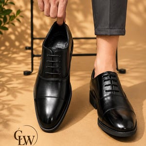 May include: A pair of black leather oxford shoes featuring a cap toe design, tonal black laces, and a low heel. The shoes have a smooth, polished finish and a structured silhouette. The logo ClassicLeatherWalk is printed in the bottom left corner.
