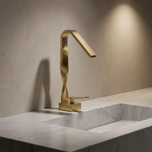 May include: A contemporary gold-coloured tap with a distinctive twisted design. The tap has a rectangular spout and a square base, set against a marble countertop and a neutral-toned wall. The design is sleek and modern.