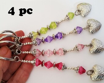 May include: Four silver keychains with heart charms. Each keychain features a different color of crystal beads: green, purple, pink, and red.