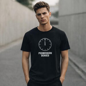 May include: Black crew neck t-shirt featuring a white clock design with the text "PERMISSION DENIED" underneath. The clock graphic indicates 12 o'clock. The shirt is made of a soft material.