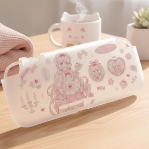 Puede incluir: Una funda protectora translúcida de acabado mate con un diseño impreso de un personaje de pelo largo, marcos en forma de corazón, velas y pequeños dulces en tonos rosa suave y blanco, con aberturas integradas para los controles del dispositivo.