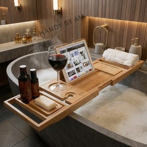 May include: A bamboo bathtub tray with a wine glass, tablet, and soap. The tray is over a bathtub filled with bubbles. Two bottles and a bar of soap are on the tray. The tablet displays images. The text "HANDY BY AM" is visible.