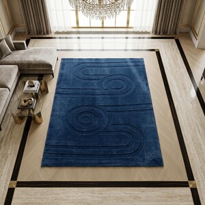 K&ouml;nnte beinhalten: Ein rechteckiger Teppich in tiefem Marineblau mit einem erhabenen, geschnitzten geometrischen Muster aus konzentrischen Kreisen und parallelen Linien, die einen strukturierten, dreidimensionalen Effekt auf der gesamten Oberfl&auml;che erzeugen.