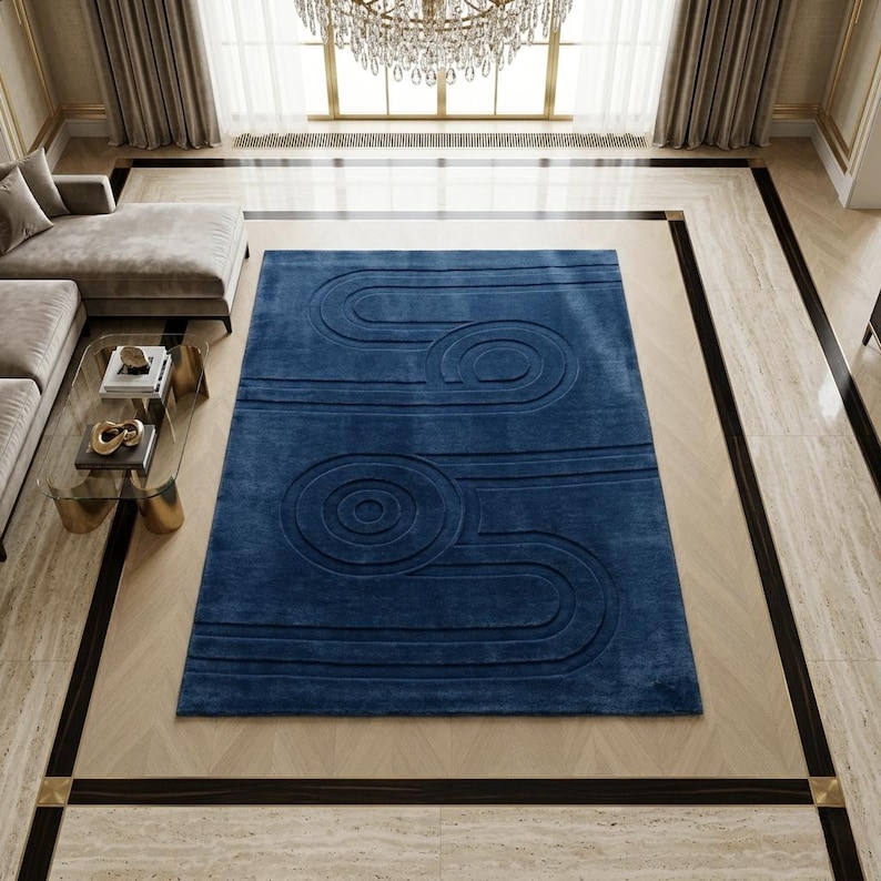 K&ouml;nnte beinhalten: Ein rechteckiger Teppich in tiefem Marineblau mit einem erhabenen, geschnitzten geometrischen Muster aus konzentrischen Kreisen und parallelen Linien, die einen strukturierten, dreidimensionalen Effekt auf der gesamten Oberfl&auml;che erzeugen.