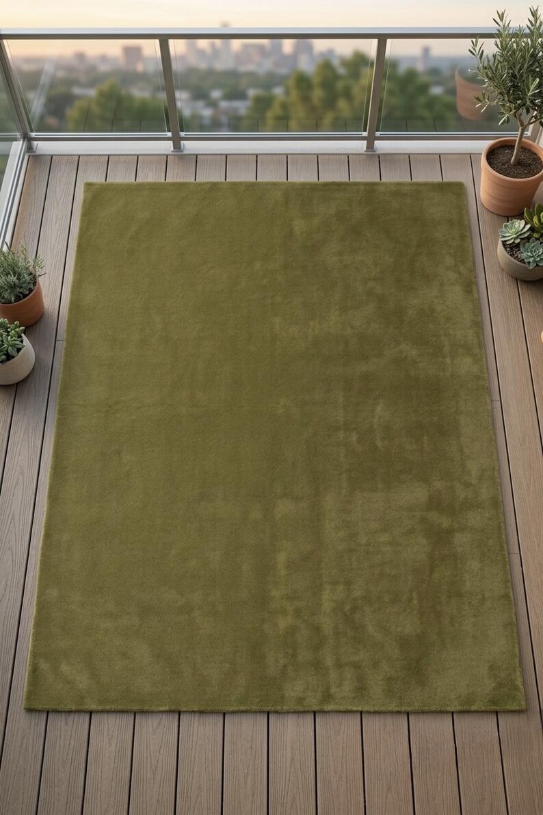 May include: A rectangular area rug in a solid olive green color with a soft, plush texture. The rug features a uniform, monochromatic surface with a short pile finish, providing a consistent appearance across the entire rectangular shape.