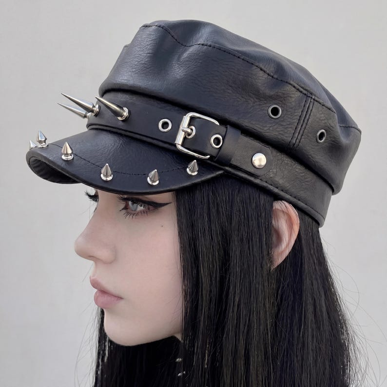Puede incluir: Gorra negra de cuero sint&eacute;tico con p&uacute;as met&aacute;licas plateadas y cierre de hebilla. La gorra tiene una visera corta con m&uacute;ltiples p&uacute;as y una banda con hebilla. Un accesorio de moda.