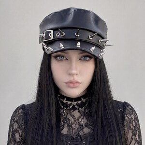 Puede incluir: Gorra de cuero negra con p&uacute;as de metal plateado y cierre de hebilla. La gorra tiene una corona redondeada y una visera corta y r&iacute;gida. Las p&uacute;as est&aacute;n espaciadas uniformemente. Un accesorio elegante.