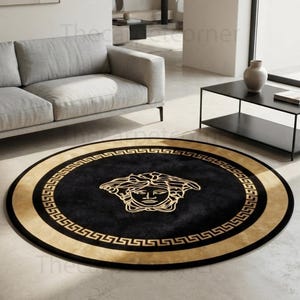 May include: A circular rug featuring a black centre with a gold Medusa head emblem, surrounded by a gold Greek key border. The design is set against a black background, creating a high-contrast look that defines the round shape of the floor covering.