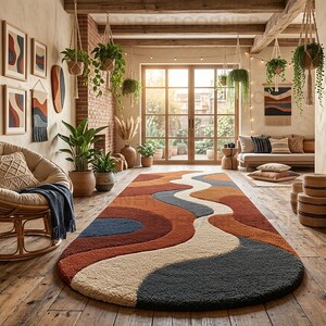 May include: An oval area rug featuring a wavy, abstract pattern in shades of terracotta, cream, navy blue, and charcoal gray. The rug has a thick, textured pile and is positioned on a wooden floor in a room with a rattan chair and hanging plants.