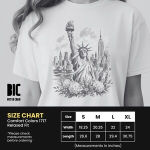 Puede incluir: Camiseta blanca con una ilustraci&oacute;n en blanco y negro de la Estatua de la Libertad y el horizonte de Nueva York. La camiseta tiene un corte relajado. La anchura es de 56 cm para la talla XL.