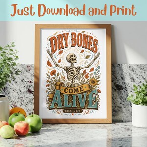 May include: A framed print featuring a skeleton with arms raised, surrounded by flowers and leaves. The text reads "DRY BONES COME ALIVE" and "EZEKIEL 37:5". The design uses orange, blue, and brown tones on a white background with a light wood frame.