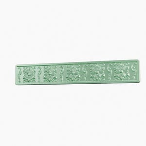 May include: A rectangular, light mint green decorative molding strip featuring a repeating embossed pattern of stylized flowers and scrolling vine motifs. The piece has a smooth, uniform finish and a raised relief design across its entire surface.