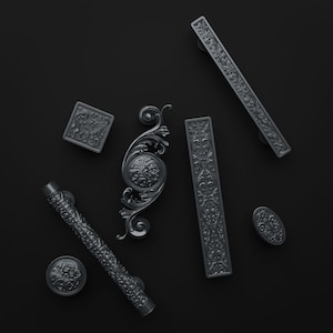 Può includere: Una collezione di sei pomelli e maniglie per mobili in nero opaco, tra cui due lunghe maniglie rettangolari, un pomello quadrato, uno rotondo, uno ovale e una maniglia curva decorata, tutti con intricati motivi floreali e a volute in rilievo.