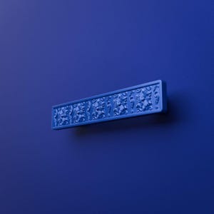 Könnte beinhalten: Ein rechteckiger Möbelgriff in einem einheitlichen tiefen Blau. Der Griff weist ein sich wiederholendes florales Prägemuster auf der gesamten Vorderseite auf, wobei ein flacher, glatter Rand die komplexen, erhabenen botanischen Designdetails einrahmt.