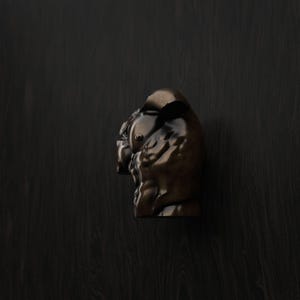 Op de afbeelding: Een donkerbruine, gepolijste houten meubelknop in de vorm van een gestileerde stierenkop. De knop heeft een glad, reflecterend oppervlak met uitgesneden details die de oren, de snuit en de gespierde nekstructuur van het dier in vorm brengen.