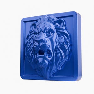 Op de afbeelding: Blauwe leeuwenkopsculptuur in een vierkante lijst. De leeuw heeft een gedetailleerde manen en een open mond, die zijn tanden laat zien. De sculptuur is een massief, driedimensionaal stuk met een glanzende afwerking, geschikt voor wanddecoratie.