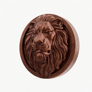 Op de afbeelding: Een gedetailleerde, bruine, cirkelvormige reliëfsculptuur van een leeuwenkop. De manen van de leeuw stromen en zijn ogen zijn gesloten. De sculptuur is geplaatst in een cirkelvormig frame, waardoor een driedimensionaal effect ontstaat.