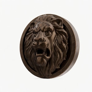 Op de afbeelding: Een bronzen, ronde wandsculptuur met een reliëf van een brullende leeuwenkop. De manen en gezichtskenmerken van de leeuw zijn fijn gebeeldhouwd, wat een dramatische en krachtige uitstraling creëert. De sculptuur is geplaatst in een cirkelvormig frame.