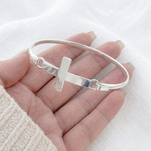 Pulsera rígida con cruz de plata de ley, acabado martillado o liso. Joyería cristiana.