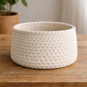 Op de afbeelding: Een set van drie keramische nestkommen in verschillende maten. De kommen hebben een gespikkelde, gebroken witte glazuur met een licht getextureerd oppervlak. Elke kom heeft een afgeronde vorm en een minimalistisch ontwerp.