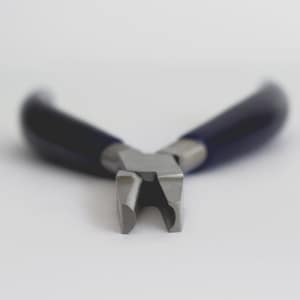 Può includere: Una tronchese frontale in metallo con testa in acciaio color argento dotata di bordi taglienti piatti e affilati e manici lisci rivestiti in blu scuro. L'utensile è posizionato con le ganasce di taglio rivolte in avanti, mostrando una struttura robusta.