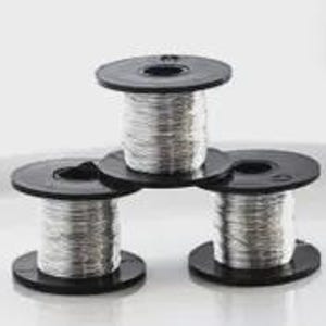 Puede incluir: Tres bobinas de plástico negro apiladas en forma de pirámide, cada una envuelta con un hilo metálico plateado fino. Las bobinas tienen un diseño circular con un orificio central, y el hilo plateado está enrollado firmemente alrededor del núcleo.