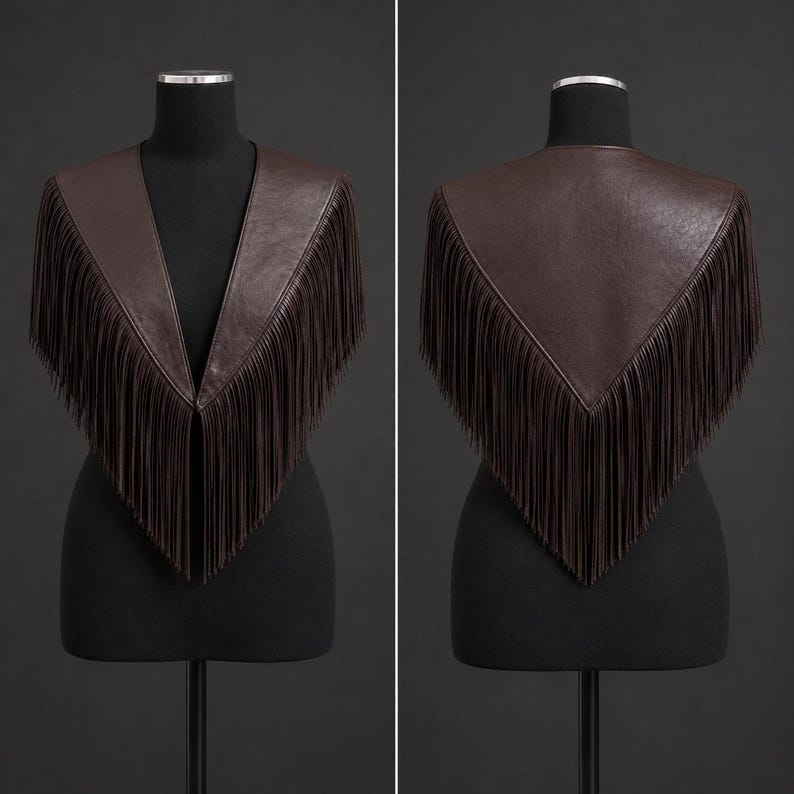 May include: A dark brown leather shawl featuring a V-shaped neckline and long, flowing fringe trim along the edges. The garment is displayed on a mannequin, showing both the front view with open panels and the back view with a pointed hemline.