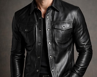 May include: A black leather jacket with a button-up front, two chest pockets, and a collared neckline. The jacket has long sleeves and a classic, tailored fit. The leather appears smooth and has a slight sheen. The jacket is worn over a black shirt.