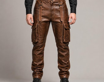 May include: Brown leather cargo pants featuring a distressed finish, two large side pockets with flaps, and two vertical leather straps attached to the front waistband. The pants are paired with a black long-sleeved shirt and black leather boots.