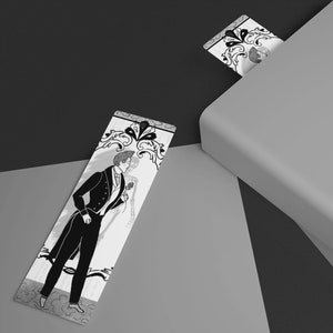 May include: Two black and white bookmarks with a decorative design featuring a couple in formal attire. The bookmark on the left is lying flat on a light grey surface. The bookmark on the right is partially sticking out of a closed book.