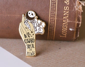 May include: Gold-toned enamel pin featuring a hand holding a crescent moon and stars with the text "No Coward Soul is Mine".