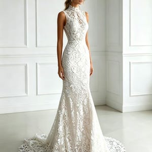 Puede incluir: Un vestido de novia blanco sin mangas con cuello alto y silueta de sirena. El vestido está hecho de una delicada tela de encaje con patrones florales. El vestido tiene una larga cola.