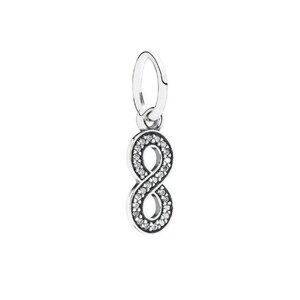 May include: A silver-toned infinity symbol charm featuring a polished metal frame encrusted with numerous small, clear, sparkling stones. The charm includes a smooth, oval-shaped bail at the top for attachment to a chain or bracelet.