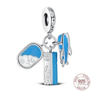 Könnte beinhalten: Ein silberner Charm mit einem hängenden Design. Der Charm hat eine blaue und weiße Wolke, einen blauen und weißen Delfin und ein rechteckiges Stück mit dem Wort "GO" und einem Wellenmuster. Der Charm ist mit "925" und "REAL STERLING" gekennzeichnet.