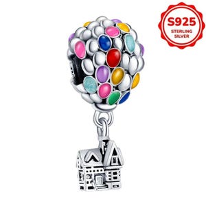 Puede incluir: Un charm de plata con un diseño de globo aerostático colorido y un colgante de casa. El globo está adornado con orbes de varios colores, incluyendo rosa, azul, amarillo y verde. El charm está marcado con "S925 STERLING SILVER".