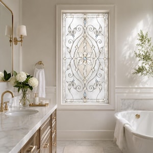 May include: A rectangular window film featuring a decorative leaded glass pattern with a central floral motif, scrolling leaf accents, and small blue jewel-toned inserts. The design uses clear and frosted textures to create a stained glass effect.