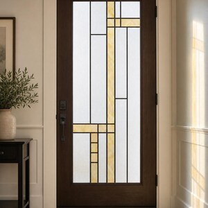 May include: A dark brown wooden door featuring a large rectangular glass insert with a geometric pattern. The glass is divided by thin black lines into white frosted sections and translucent amber-colored rectangular glass accents.