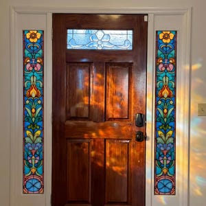 Puede incluir: Una puerta de madera oscura con una vidriera y dos paneles laterales de vidriera. La puerta tiene una ventana rectangular en la parte superior. La vidriera presenta diseños florales coloridos en azul, amarillo, rosa y verde.
