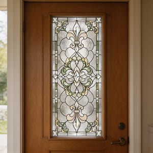 Op de afbeelding: Een middelbruine houten deur met een hoog, rechthoekig glas-in-loodpaneel. Het glaspaneel toont een symmetrisch patroon met heldere, getextureerde en lichtgroene glassegmenten, geaccentueerd door gefacetteerde heldere glazen juwelen.