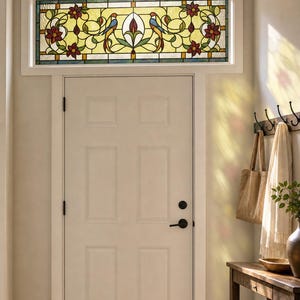May include: A rectangular stained glass transom window featuring a central floral motif flanked by two birds with blue and orange plumage, set against a yellow background with red flower accents, installed above a white six-panel interior door.