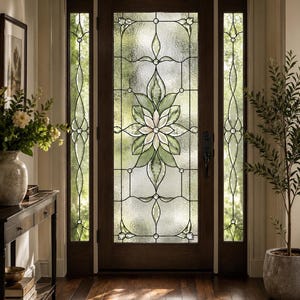 Può includere: Una porta d'ingresso in legno scuro con un pannello centrale in vetro colorato con un motivo floreale verde e bianco. La porta è affiancata da due strette finestre laterali verticali con motivi in vetro abbinati, il tutto in un telaio in legno.