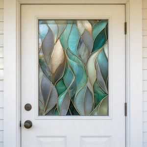 Puede incluir: Una puerta blanca con un panel de vidrio rectangular con un diseño de vidriera. El diseño muestra un patrón fluido de formas de hojas en tonos de verde azulado, verde, gris y dorado, con contornos dorados. La puerta tiene un pomo redondo.