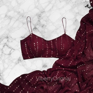May include: A burgundy-colored, sequined crop top with thin straps and a matching draped fabric. The top features vertical rows of sequins. The text "ViberryOriginal" is visible on the fabric.