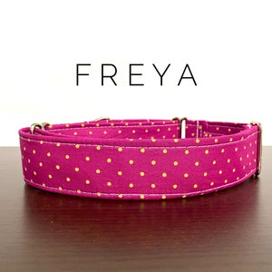 May include: A pink dog collar with small yellow polka dots. The collar is made of fabric and has a metal buckle. The collar is labeled "FREYA".