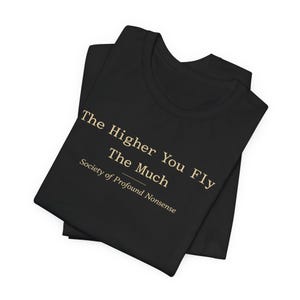 May include: Black t-shirt featuring the text "The Higher You Fly The Much" and "Society of Profound Nonsense" in gold. The t-shirt is folded, suggesting it's new and made of a soft fabric.